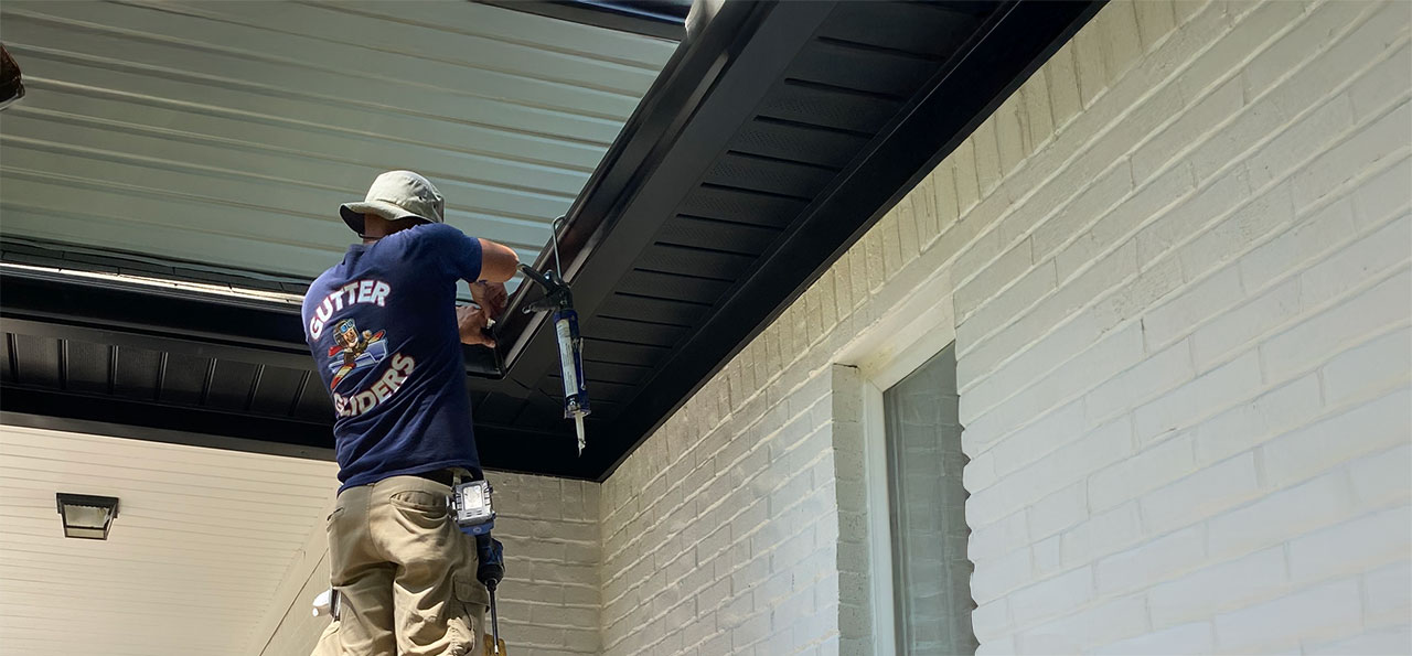 A person from Gutter Gliders cleaning out gutters for a homeowner.